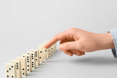Gri arkaplanda domino taşları olan kadın el, yakın plan.