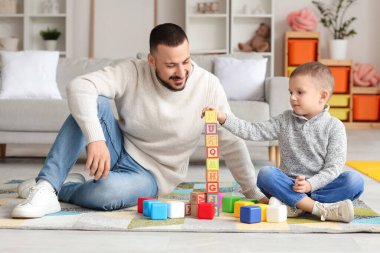 Mutlu baba ve küçük oğlu evlerinde renkli küplerle kule inşa ediyorlar.