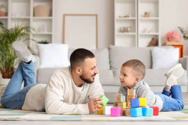 Mutlu baba ve küçük oğlu evde renkli küplerle oynuyorlar.