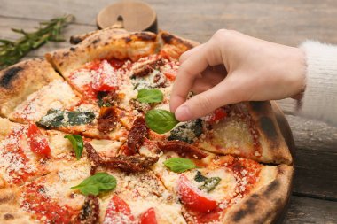 Lezzetli pizza margaritasına fesleğen yaprağı koyan kadının eli.