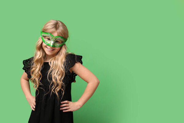 Забавная девочка в карнавальной маске на зеленом фоне