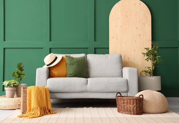 Interior of stylish living room with grey sofa, baskets and plants
