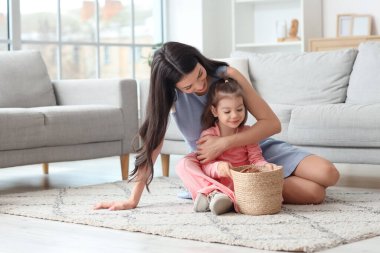 Genç anne evde küçük kızına sepetle sarılıyor.