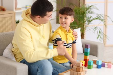 Baba, evinde renkli küplerle oğluna sarılıyor.