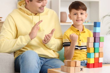 Baba, küçük oğlu için renkli küplerle el çırpıyor.