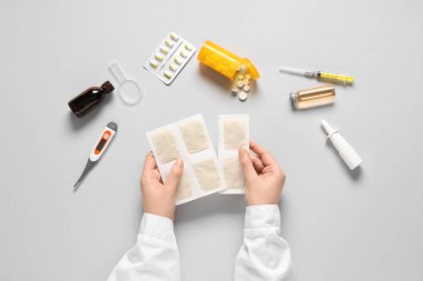 Arka planda hardal sıva ve tıbbi malzemeler tutan bir kadın.