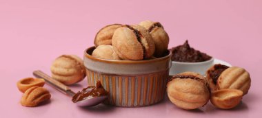 Bir kase tatlı ceviz şekilli kurabiye ve pembe arka planda kaynamış konsantre süt.