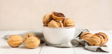 Bir kase tatlı ceviz şekilli kurabiye ve hafif arka planda kaynamış konsantre süt.