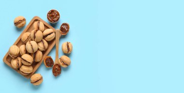 Tatlı ceviz şekilli kurabiyelerin bileşimi kaynamış yoğun sütle birlikte açık mavi arkaplanda metin için boşluk, üst görünüm