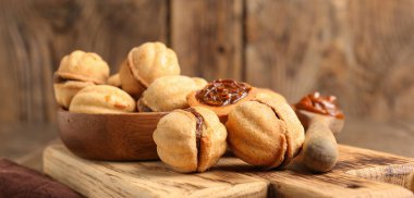 Ahşap arka planda kaynamış konsantre sütle ceviz şeklinde kurabiyeler, yakın plan.