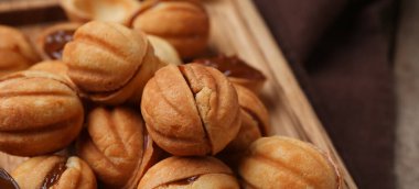 Bir sürü tatlı ceviz şekilli kurabiye haşlanmış süt, yakın plan.