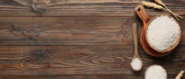 Ahşap zemin üzerinde kase dolusu çiğ pirinç, metin ve üst görünüm için yer var.