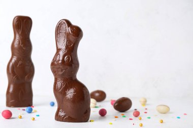 Beyaz arka planda yumurta ve çikolata parçacıkları olan Paskalya tavşanları.