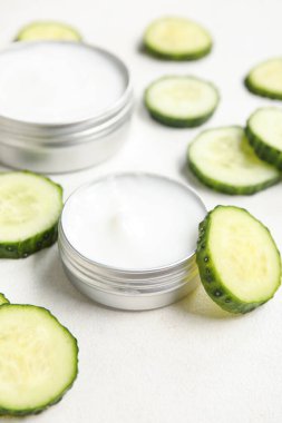 Doğal krema kavanozları ve arka planda salatalık dilimleri, yakın plan.