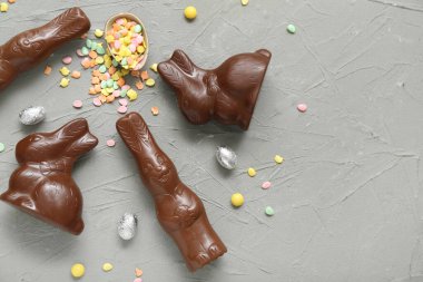 Çikolatalı Paskalya yumurtası ve gri arka planda tavşanlar.