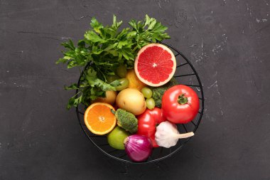 Siyah arka planda farklı taze meyve ve sebzelerle dolu sepet.