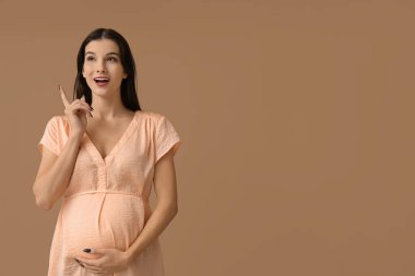 Bej arka planda düşünceli hamile bir kadın.