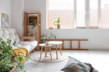 Işıl ışıl oturma odasının içinde rahat beyaz kanepe, sehpa ve bitkiler var.