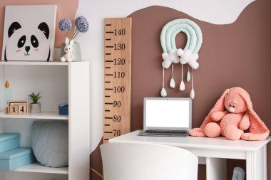 Çalışma alanı, dizüstü bilgisayarı ve ahşap stadyumu olan şık bir çocuk odası.