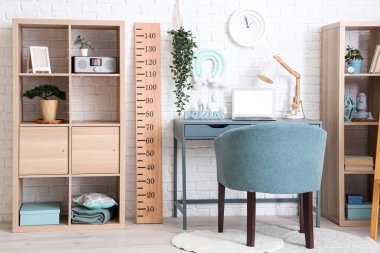 Rahat çalışma alanı, dizüstü bilgisayarı ve ahşap stadyumu olan modern çocuk odası.