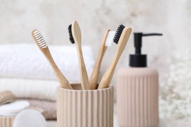 Arka planda bambu diş fırçası ve banyo malzemeleri olan tutucu, yakın plan.
