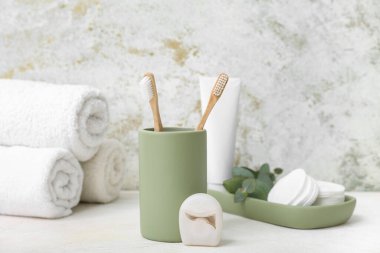 Arka planda diş fırçası ve diş ipiyle banyo malzemeleri.