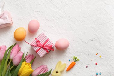 Hediye kutulu Paskalya yumurtaları ve beyaz arka planda lale çiçekleri