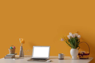 Laptoplu işyeri, Paskalya yumurtaları ve sarı duvarlı çiçekler.