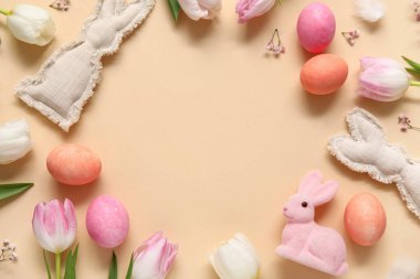 Lalelerden yapılmış çerçeve, bej arka planda Paskalya tavşanları ve yumurtalar