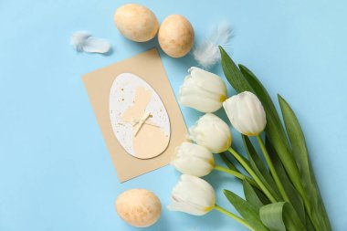 Tebrik kartı, lale ve yumurtalı kompozisyon mavi arka planda. Paskalya kutlaması