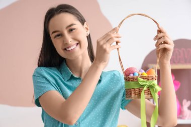 Evde paskalya yumurtası dolu sepeti olan genç bir kadın.