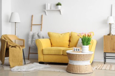 Uluslararası Kadınlar Günü için laleler ve kanepelerle aydınlık oturma odasının içinde.