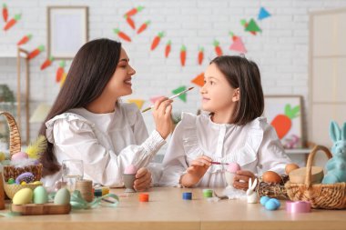 Küçük kız ve annesi mutfakta Paskalya yumurtası boyuyor.