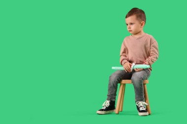 Otistik bozukluğu olan küçük bir çocuk ve yeşil arka planda oturan pop tüpü.