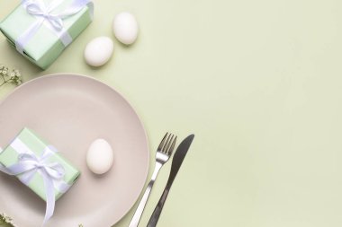 Yeşil arka planda hediyeler, çiçekler ve yumurtalarla güzel bir Paskalya masası.