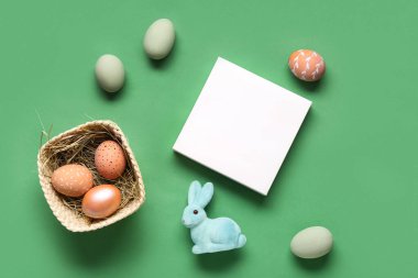 Boyanmış yumurta sepeti, Paskalya tavşanı ve yeşil arka planda boş kart. Üst görünüm