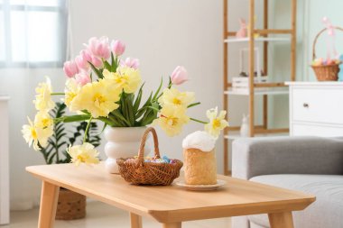 Paskalya sepetiyle güzel laleler ve oturma odasındaki masada pasta.
