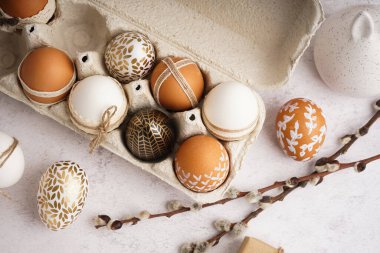 Süslü Paskalya yumurtaları ve beyaz arka planda söğüt dallarıyla kağıt tutucu.