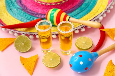 Pembe arka planda tekila ve şapka.