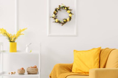 Raflı kanepe, Paskalya çelengi ve beyaz duvarın yanında dekor.