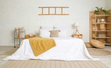 Büyük, rahat bir yatağı ve beyaz tuğla duvarlı merdiveni olan bir yatak odası.