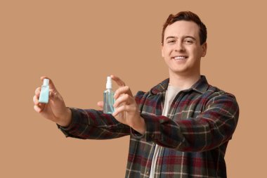 Bej arka planda dezenfektanları olan genç bir adam