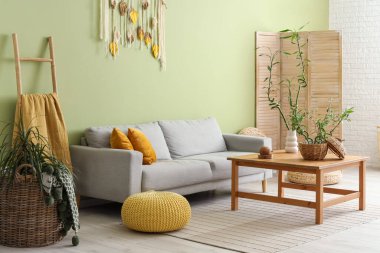 Kahve masası ve kanepenin üzerinde bambu sapları olan yeşil oturma odasının modern iç mekanı.