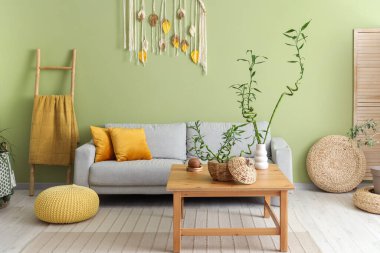 Kahve masasında bambu saplı yeşil oturma odasının içi ve rahat kanepe.