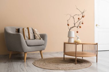 İçinde ağaç dalları ve Paskalya yumurtaları olan vazo oturma odasının iç tarafında.