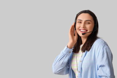 Gri arka planda kulaklık takan mutlu bayan teknik destek ajanı