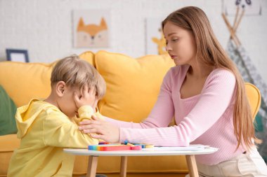 Ofisteki masada stresli bir çocukla çalışan kadın psikolog. Dünya Otizm Farkındalık Günü
