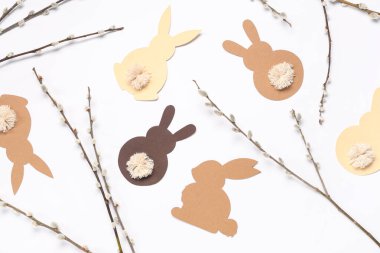 Pussy willow branches and paper bunnies on white background. Easter celebration
