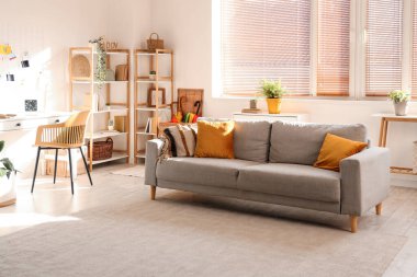 Oturma odasının içinde kanepe, bitki ve raf üniteleri var.