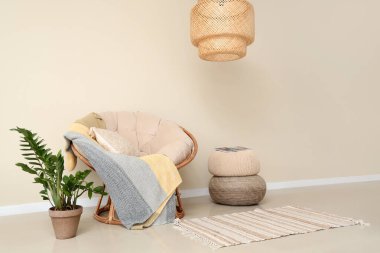 Aydınlık oturma odasının içinde koltuk, bitki ve puf var.